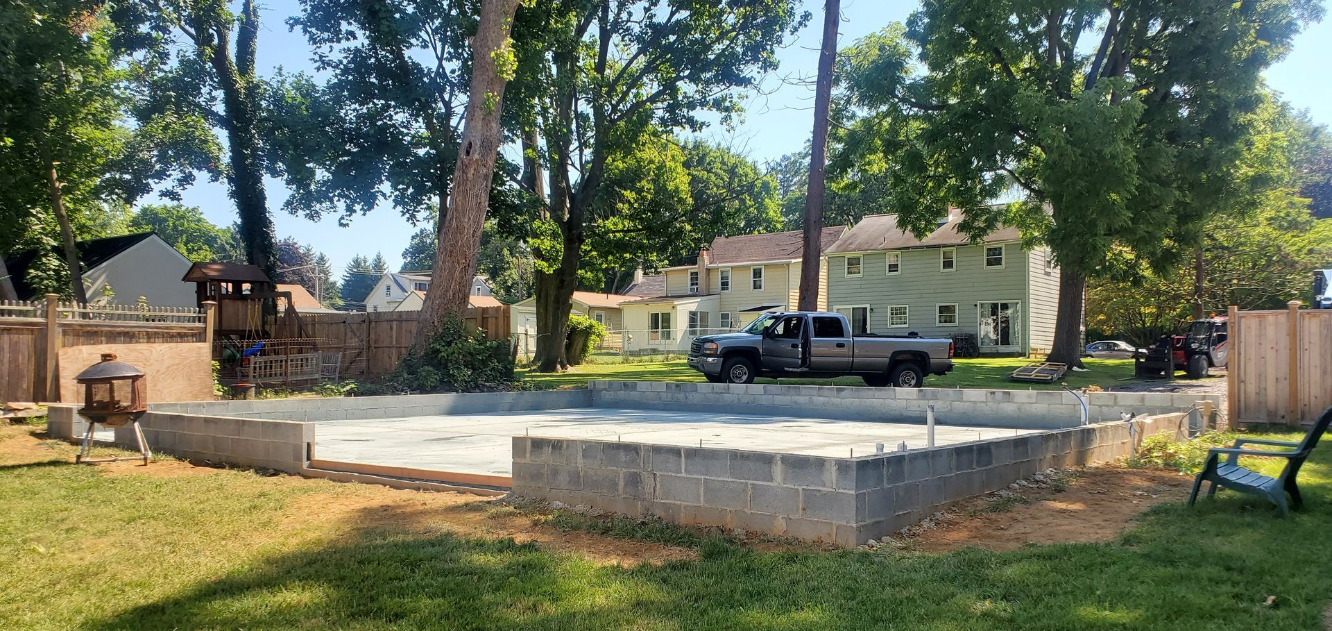 A truck is parked in the backyard of a house under construction.