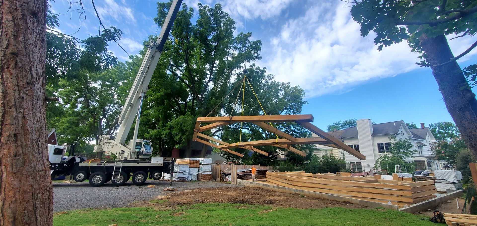 A crane is lifting a wooden structure on a construction site.