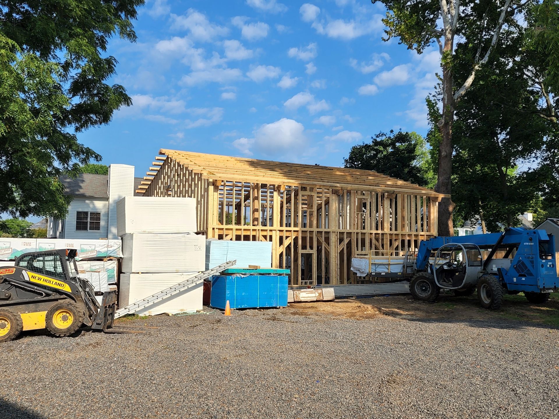 A house is being built in a lot with a tractor and a bulldozer.
