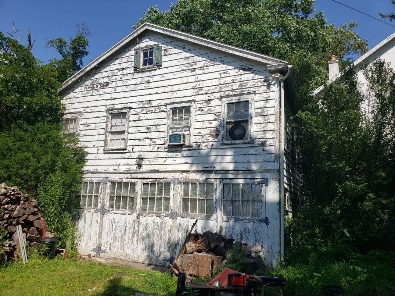 A white house with a lot of windows is sitting in the middle of a grassy field.