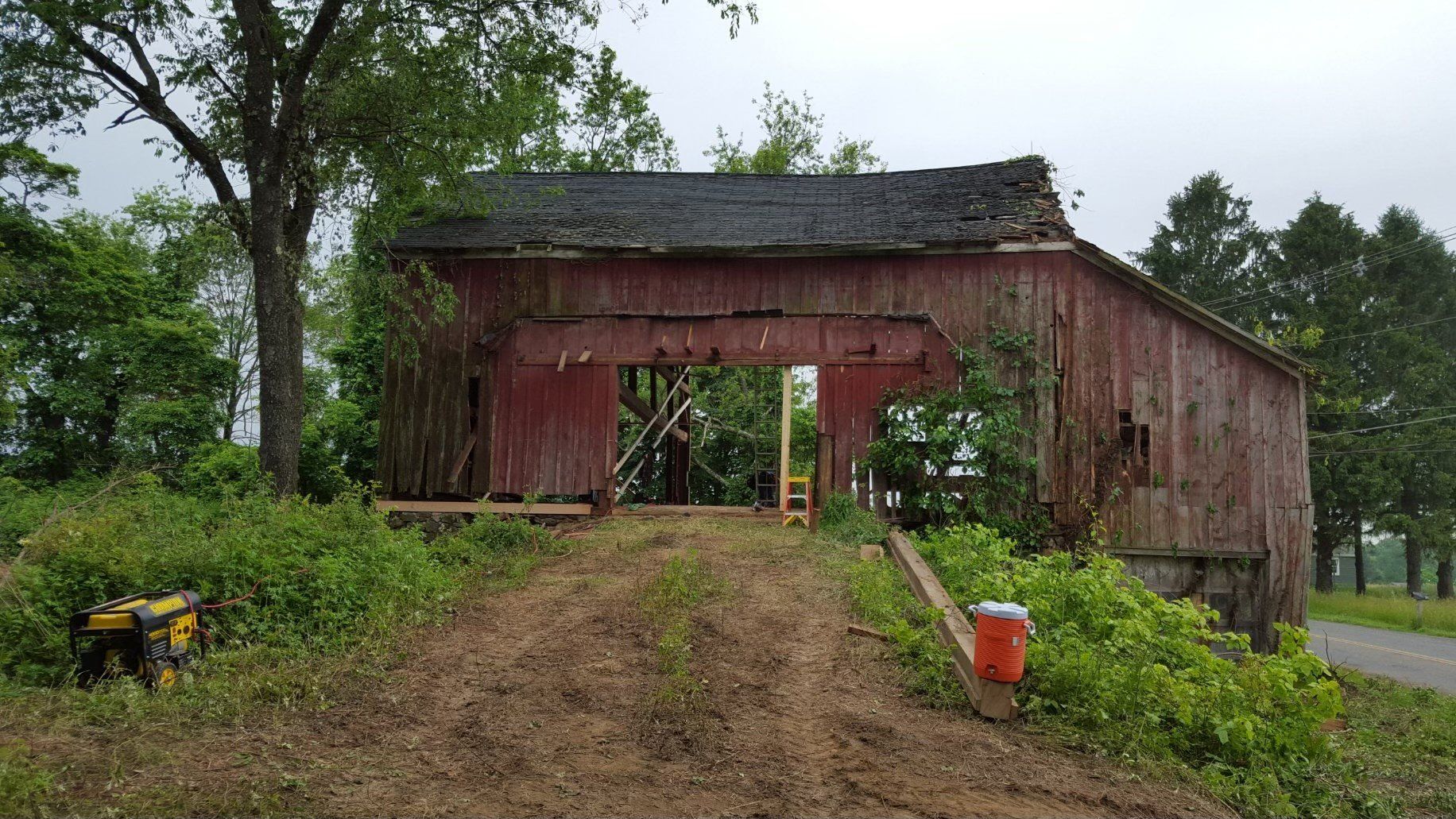 A red barn is sitting on top of a dirt hill in the middle of a field.
