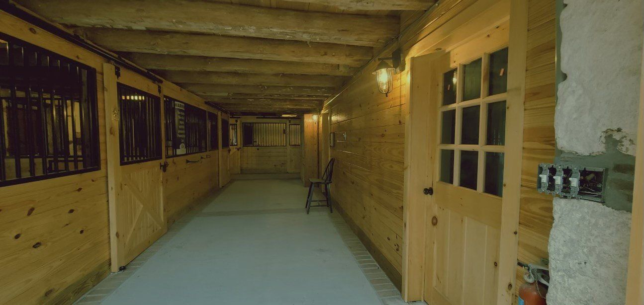 A long hallway with wooden walls and doors in a barn.