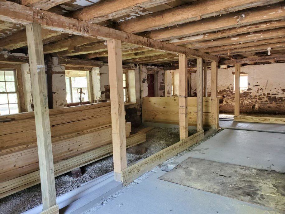 The inside of a building under construction with wooden beams and a concrete floor.