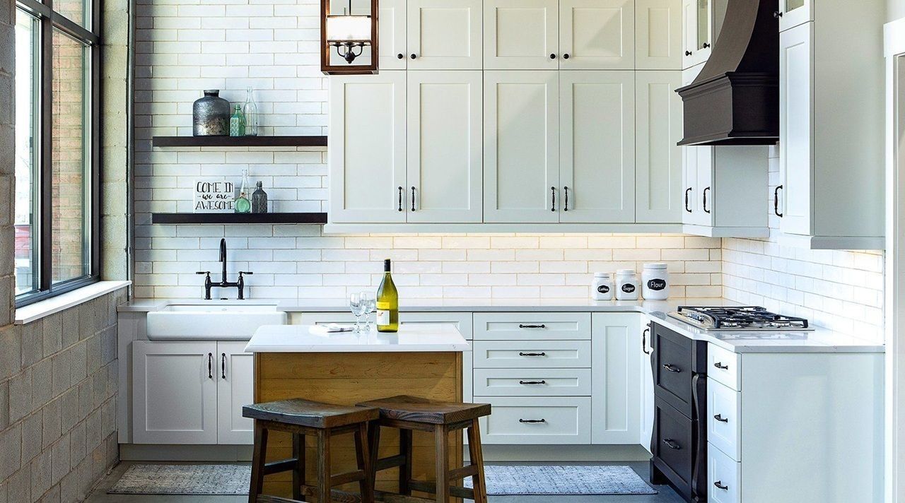 White kitchen with cabinets, stove, sink, and island; rustic stools.