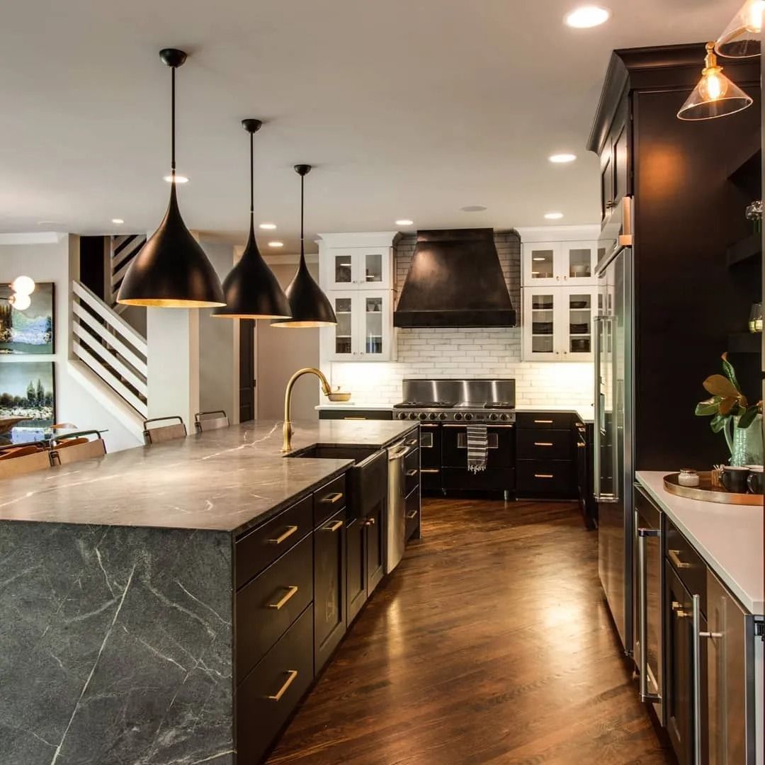 Modern kitchen with black cabinets, gray countertops, and three hanging black pendant lights.