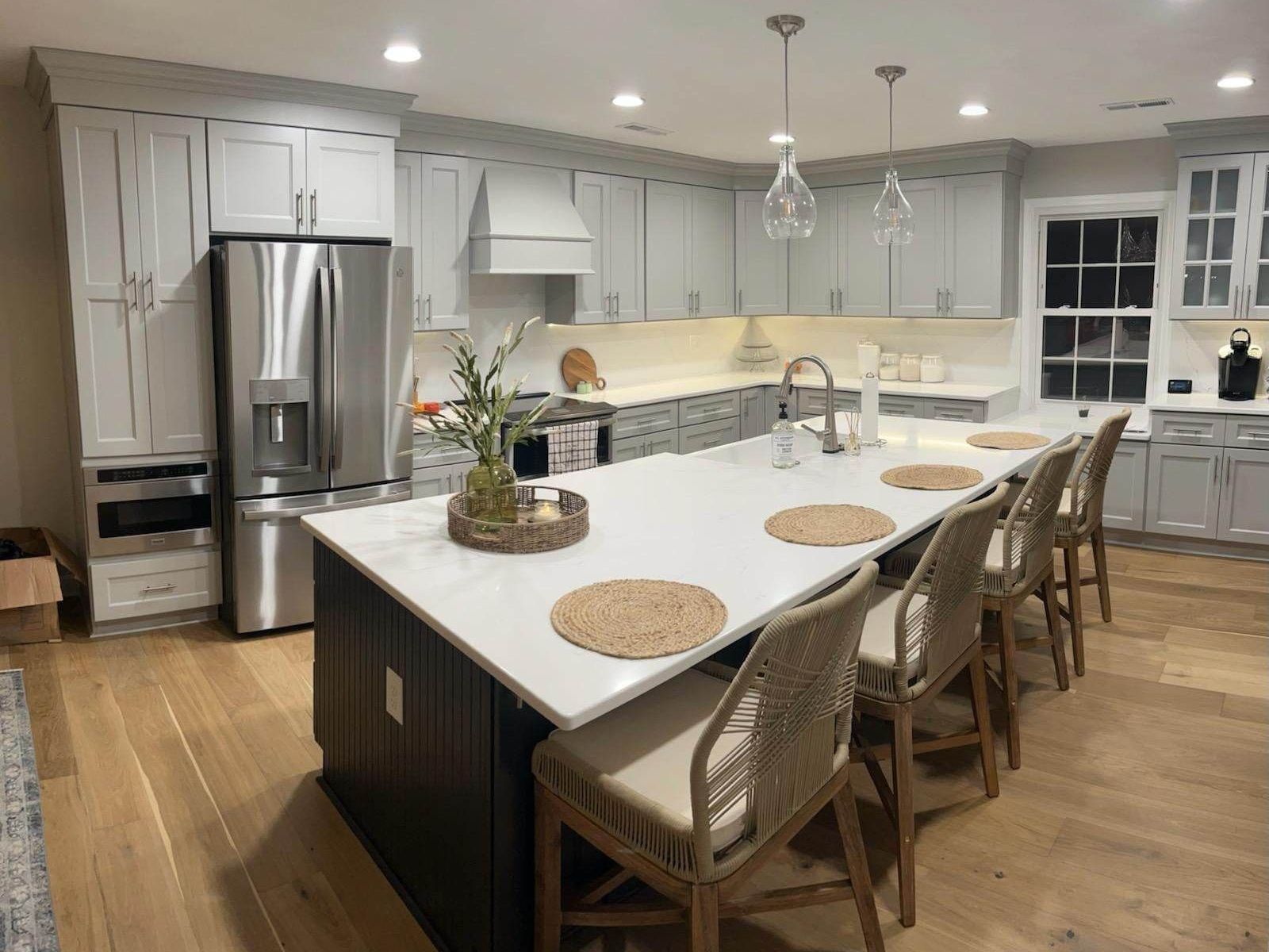 Modern kitchen with grey cabinets, stainless steel appliances, and a large island with bar seating.