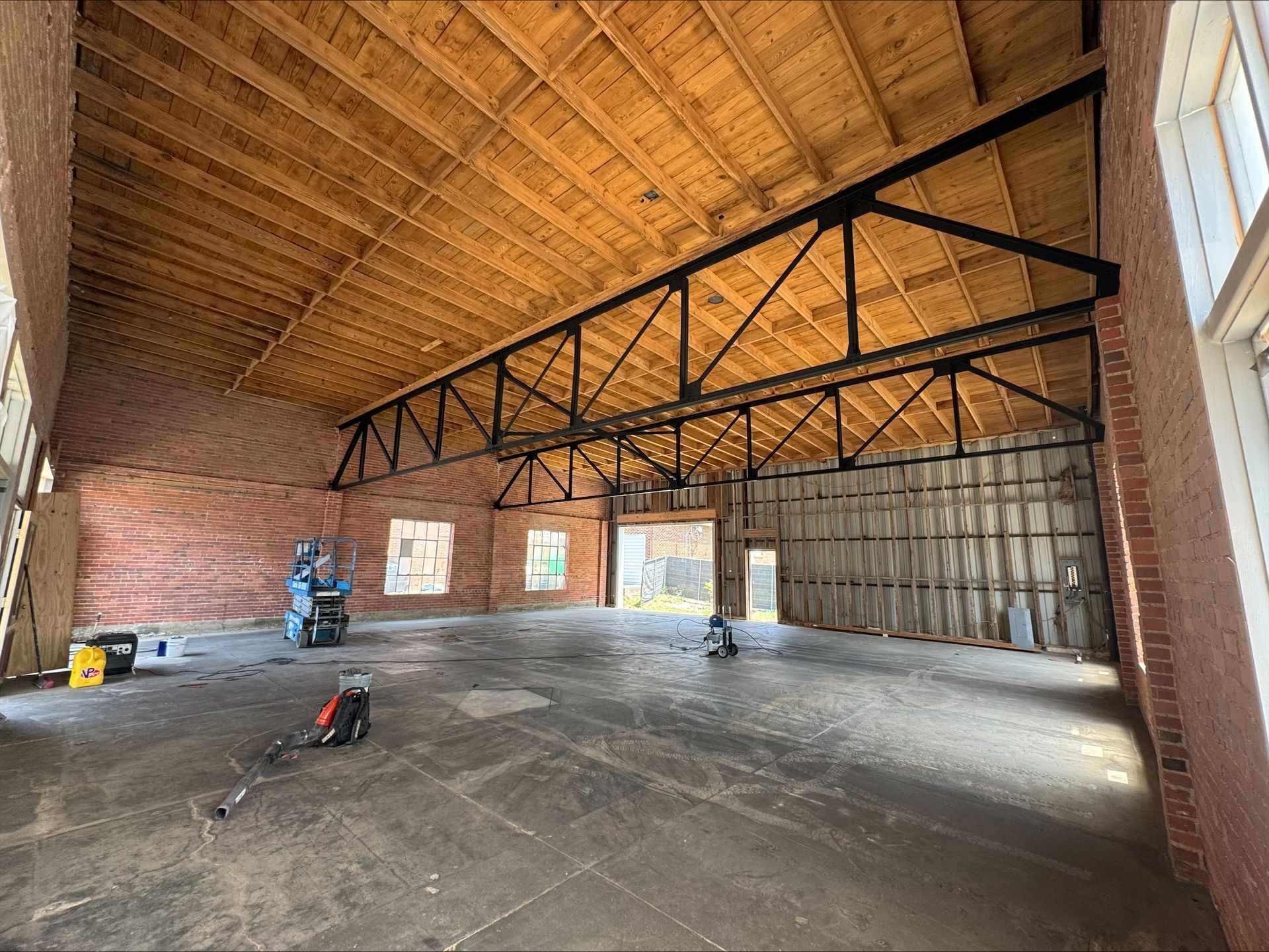 A large empty room with a wooden ceiling and brick walls.