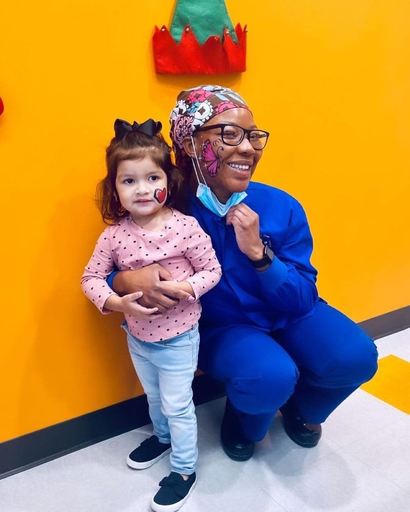 A woman in a blue uniform is holding a little girl in her arms