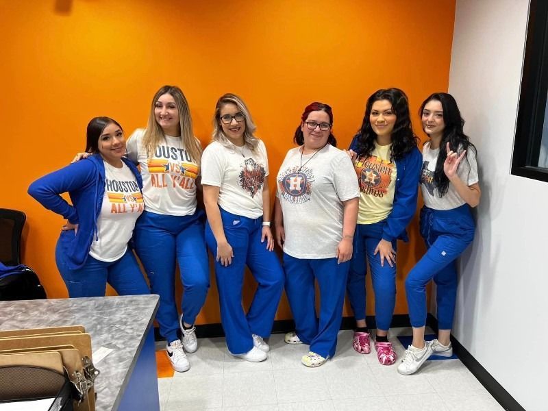 A group of women are posing for a picture in front of an orange wall