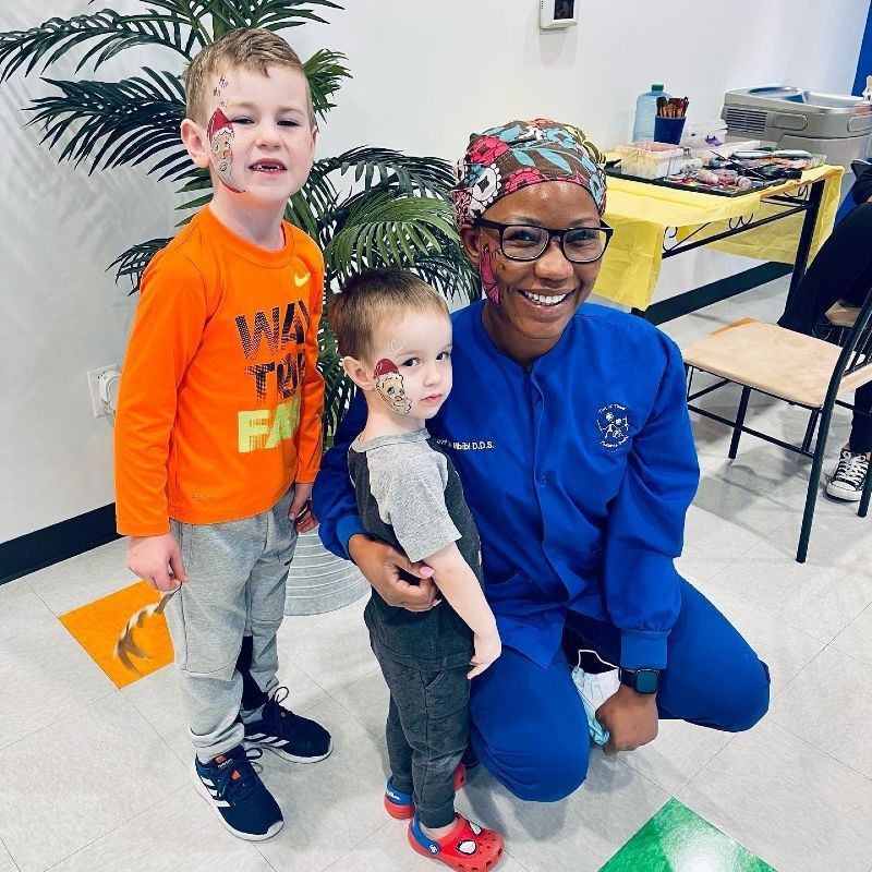 A woman in a blue jacket is posing for a picture with two children