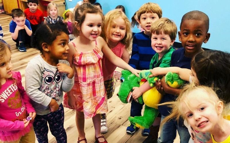 A group of children are standing around a stuffed animal.