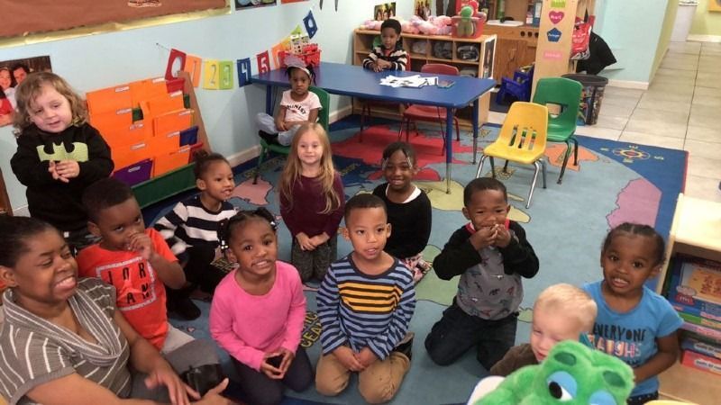A group of children are sitting on the floor in a classroom.
