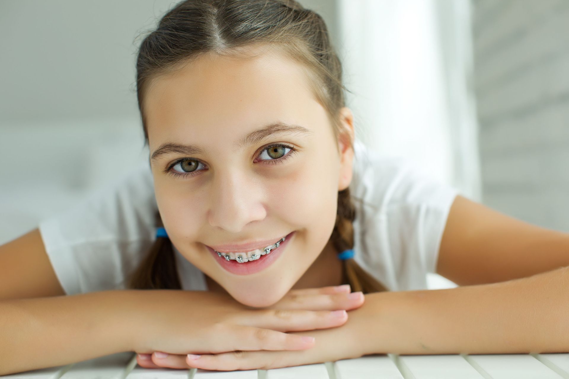 A young girl with braces is smiling while sitting at a table.