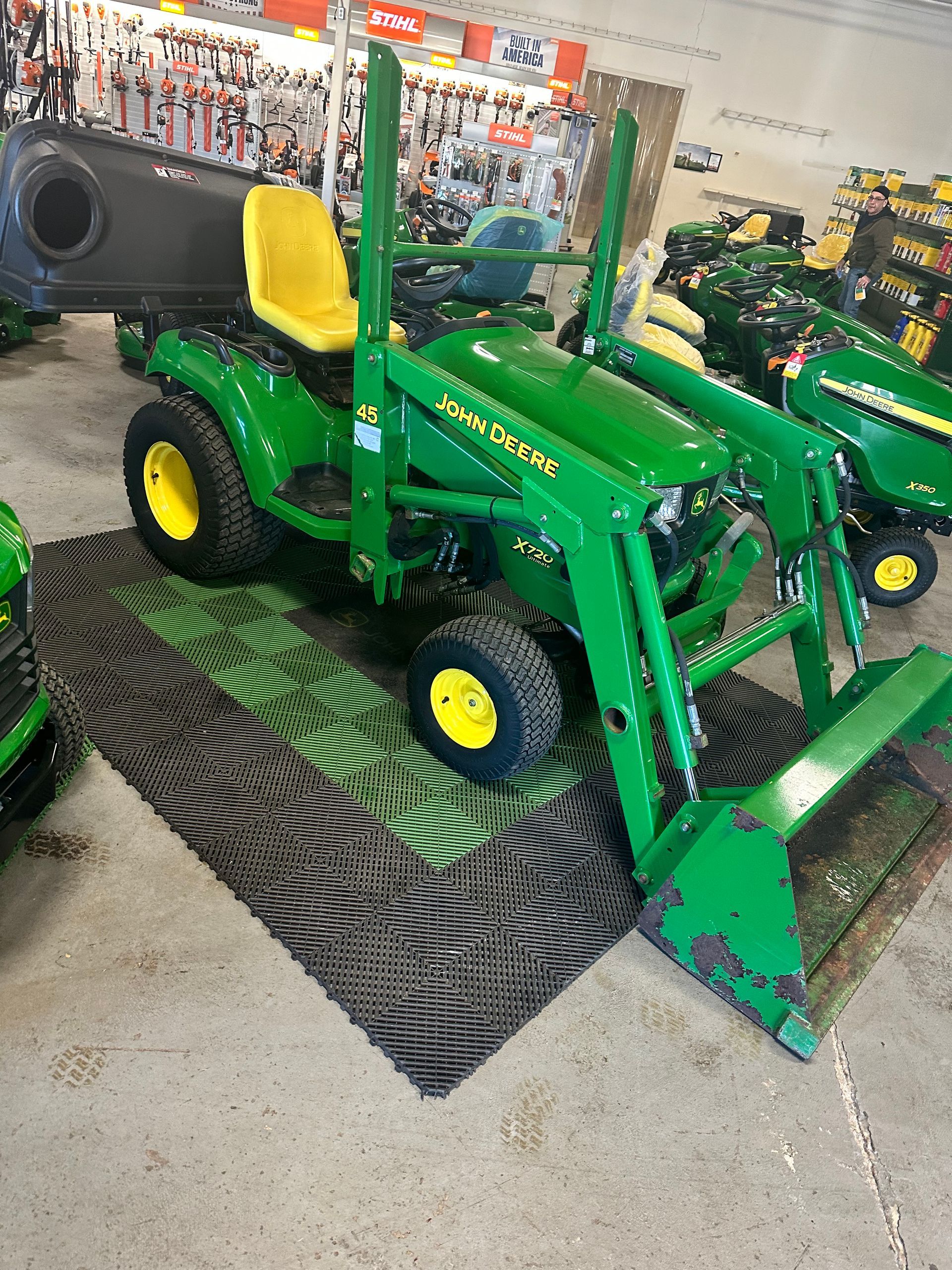 A john deere tractor is sitting on a mat in a showroom.