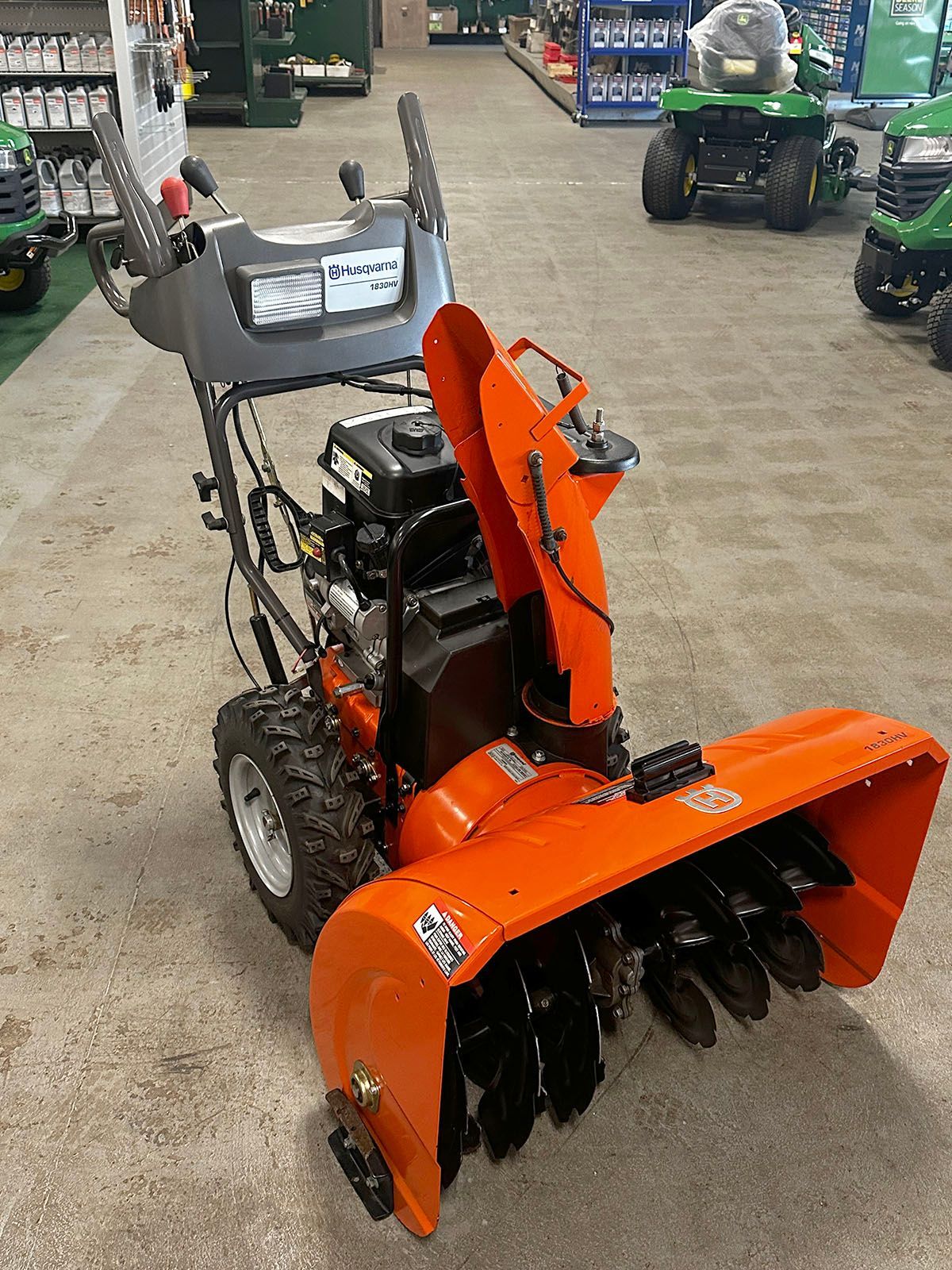 An orange snowblower is sitting in a store