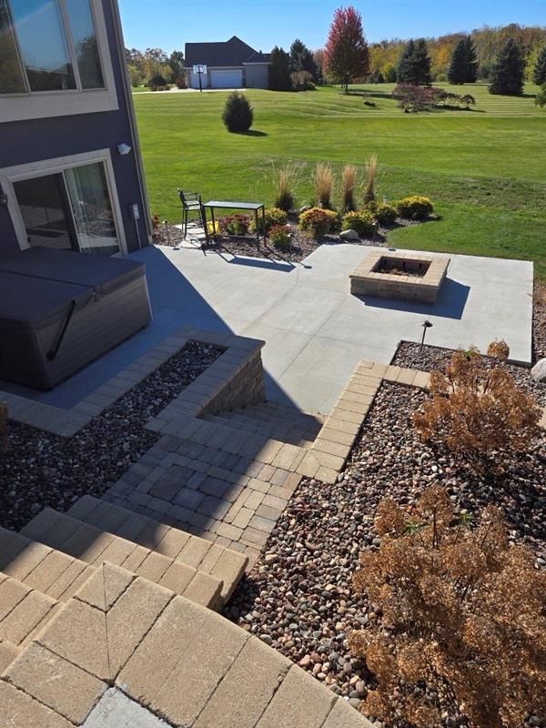 A patio with a hot tub and a fire pit