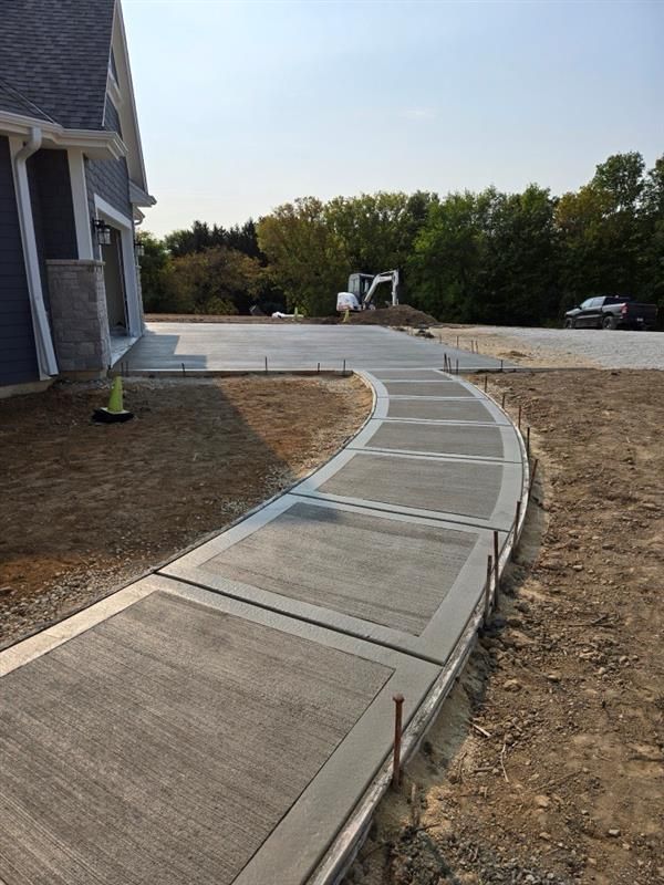 A curved concrete walkway is being built in front of a house.