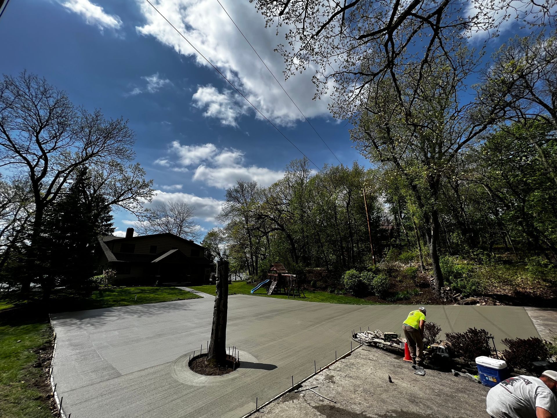 A man is laying concrete on the side of a road.