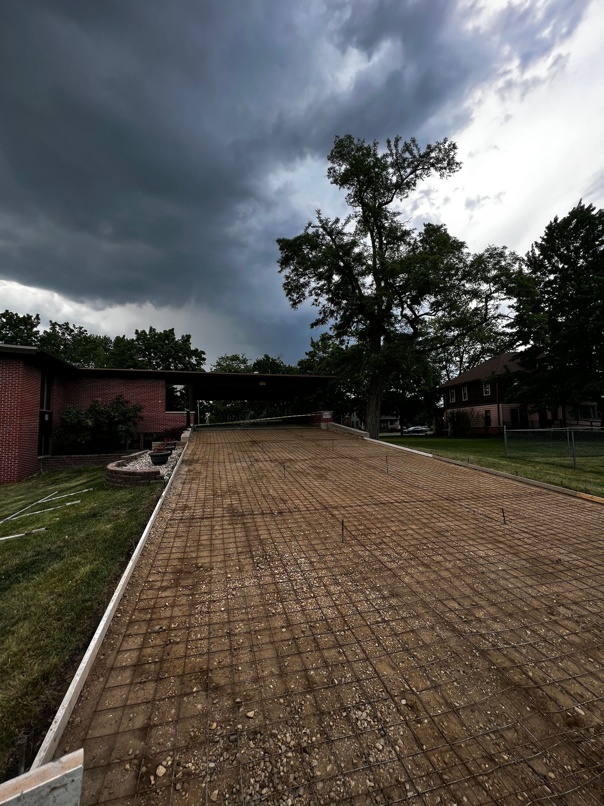A dirt road leading to a house under a cloudy sky