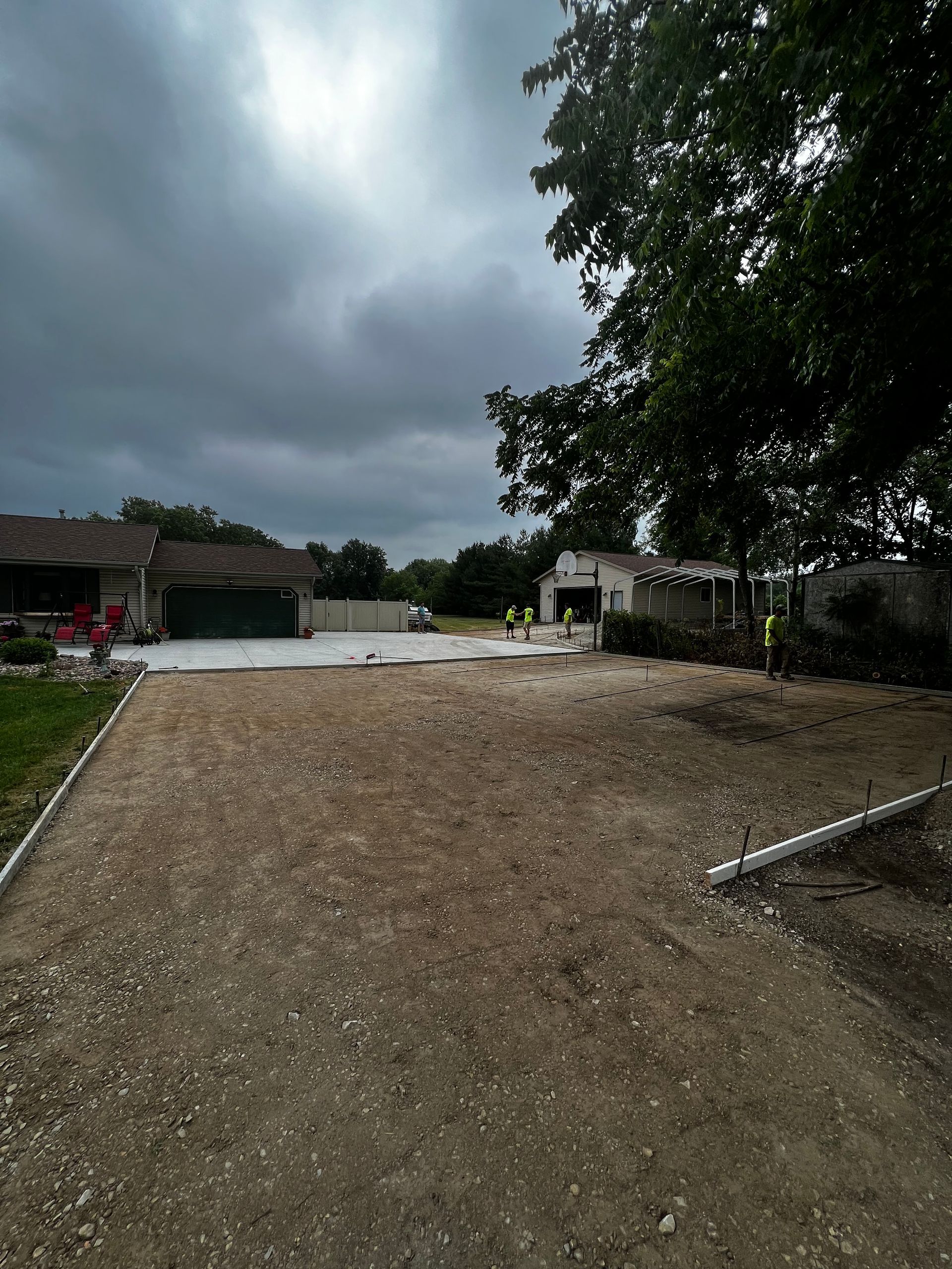 A dirt road leading to a house with a cloudy sky in the background.