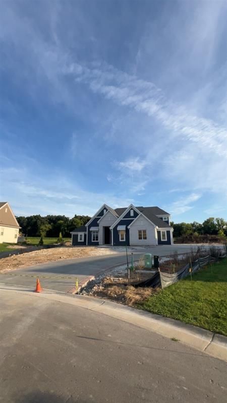 New two-story house with blue-gray siding, light stone, and a gray roof under a blue sky. Construction materials in front.