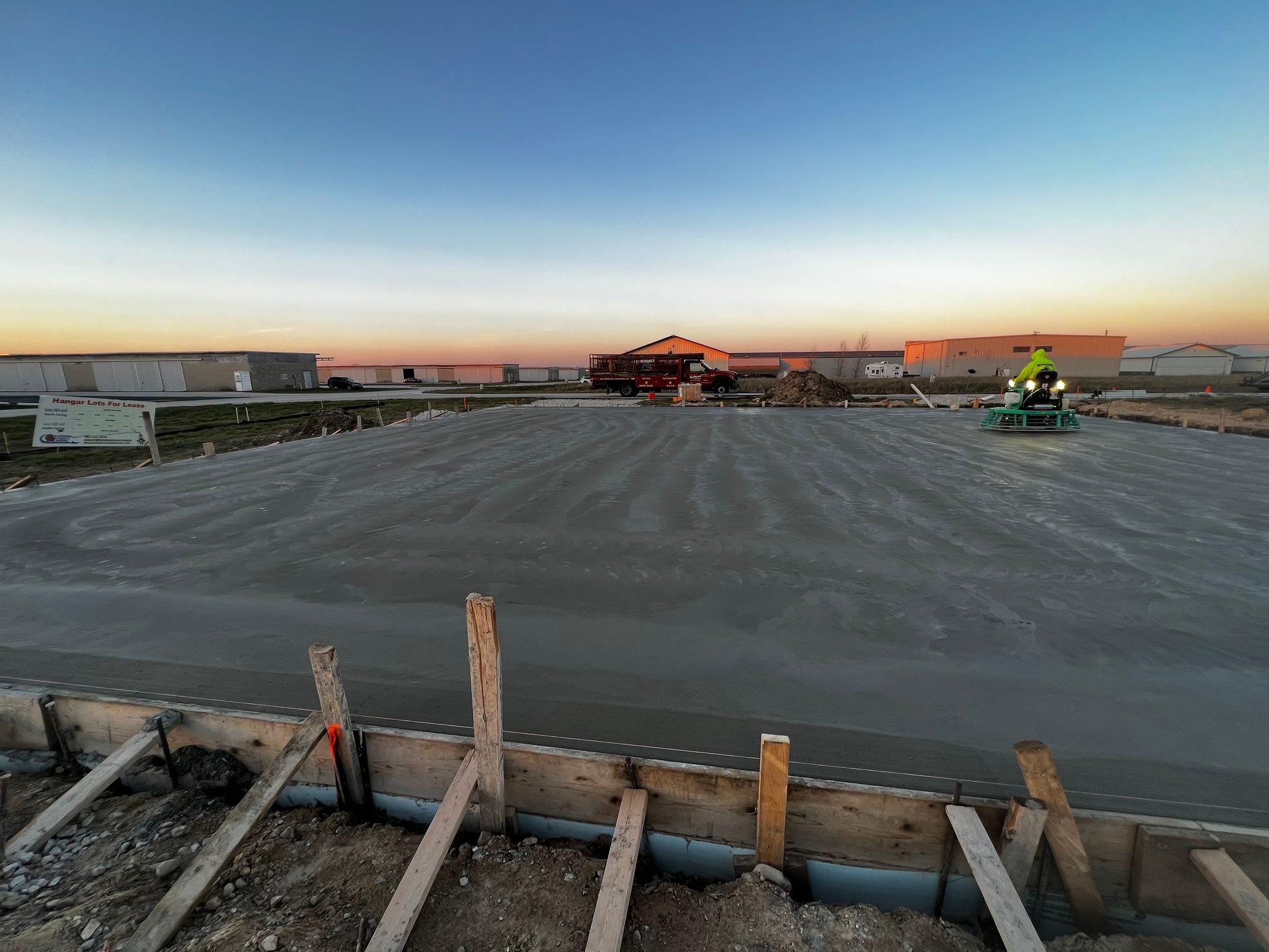 A construction site with a lot of concrete and a sunset in the background.
