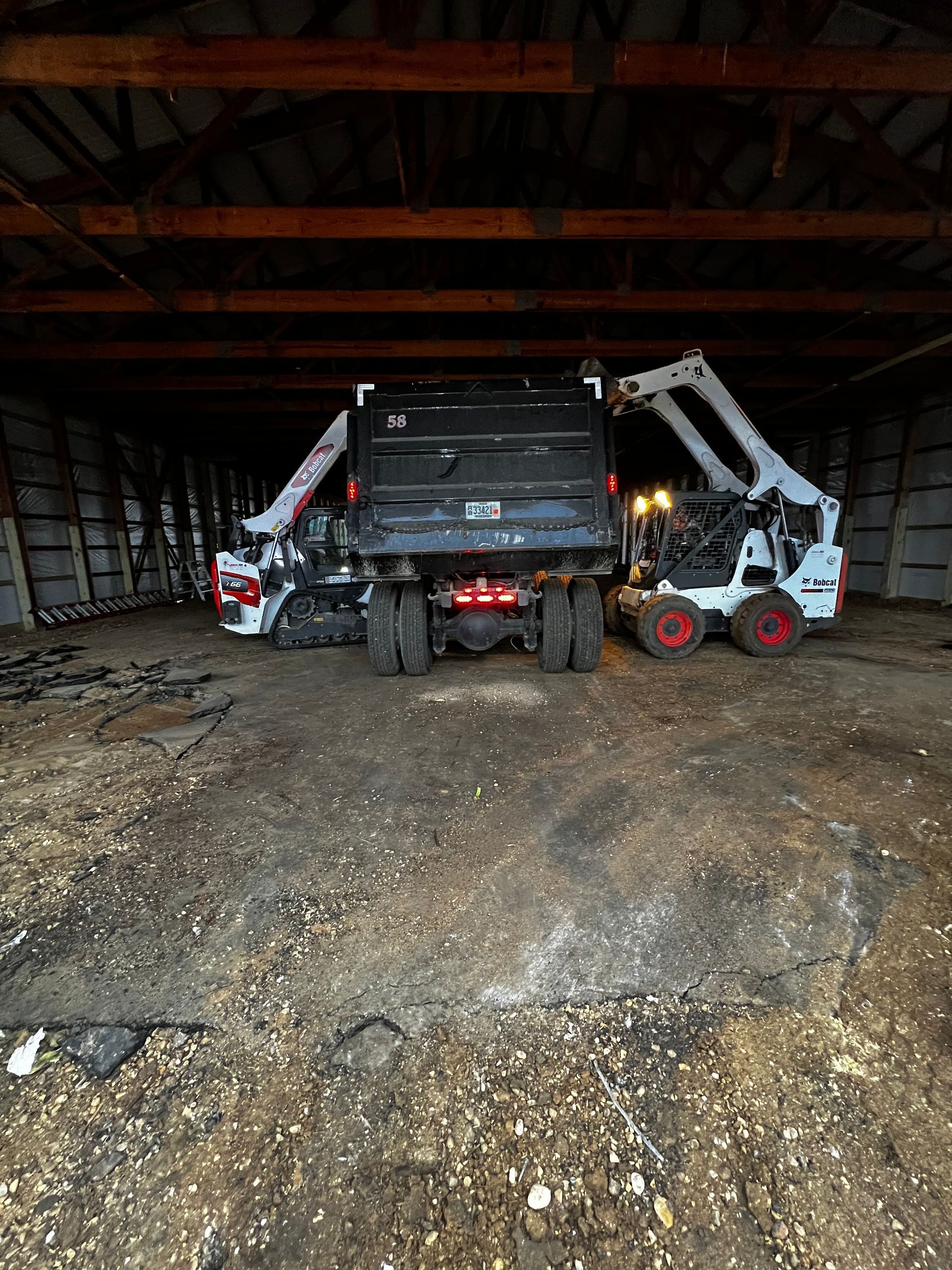 A truck and a bulldozer are parked in a barn.