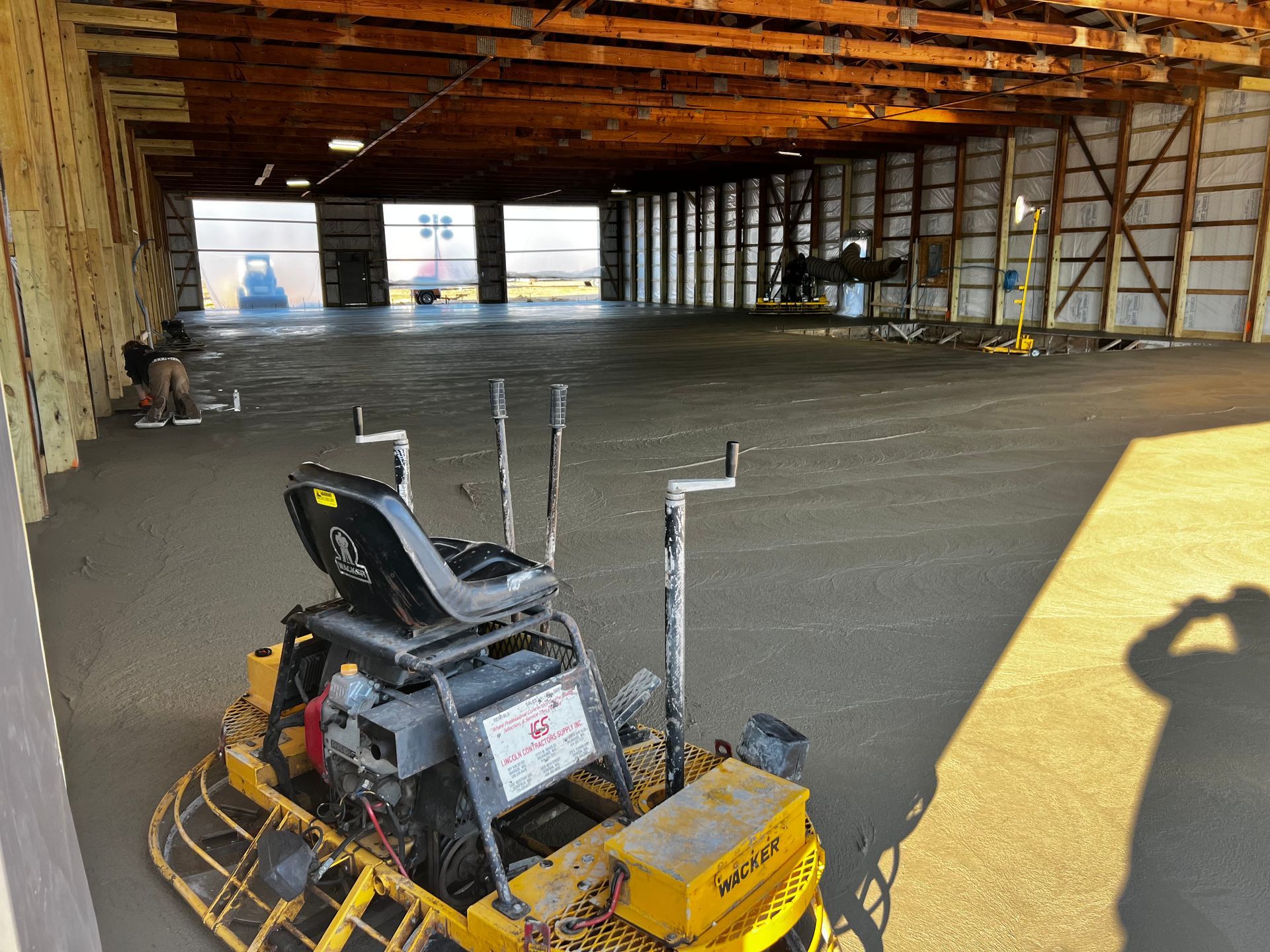 A yellow machine is sitting in a large empty warehouse.
