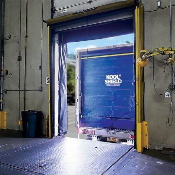 A blue truck is parked in a warehouse with the door open.