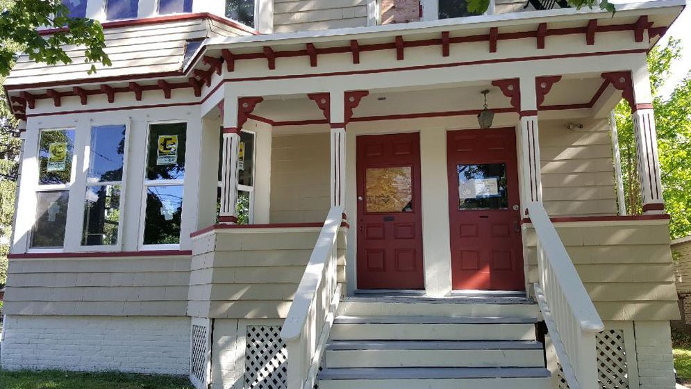 A white house with a red door and stairs