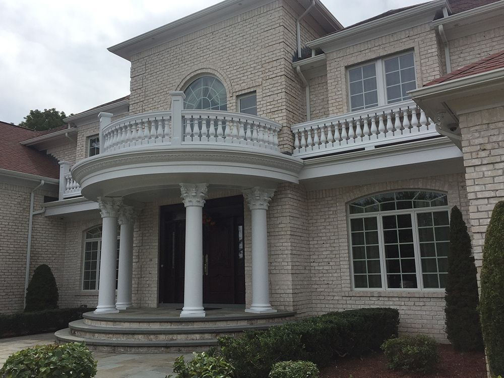 A large white brick house with a balcony and columns.