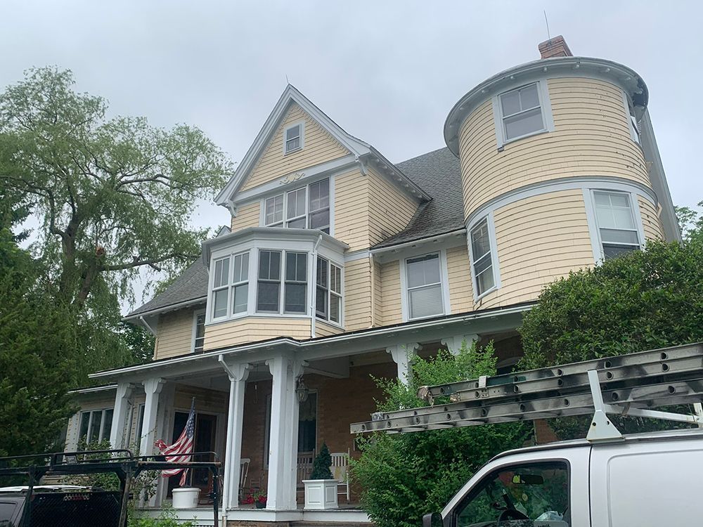 A large yellow house with a white van parked in front of it.