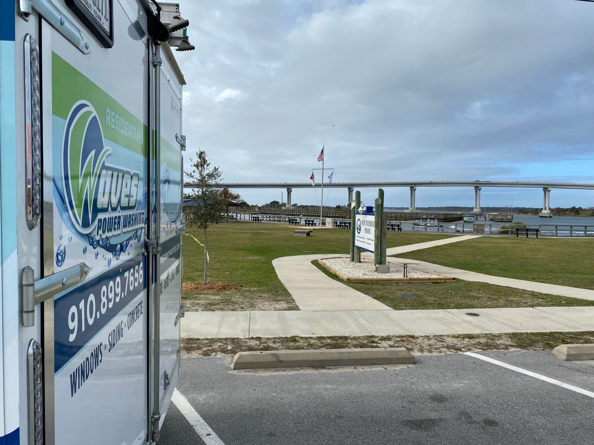 A trailer is parked in a parking lot with a bridge in the background.