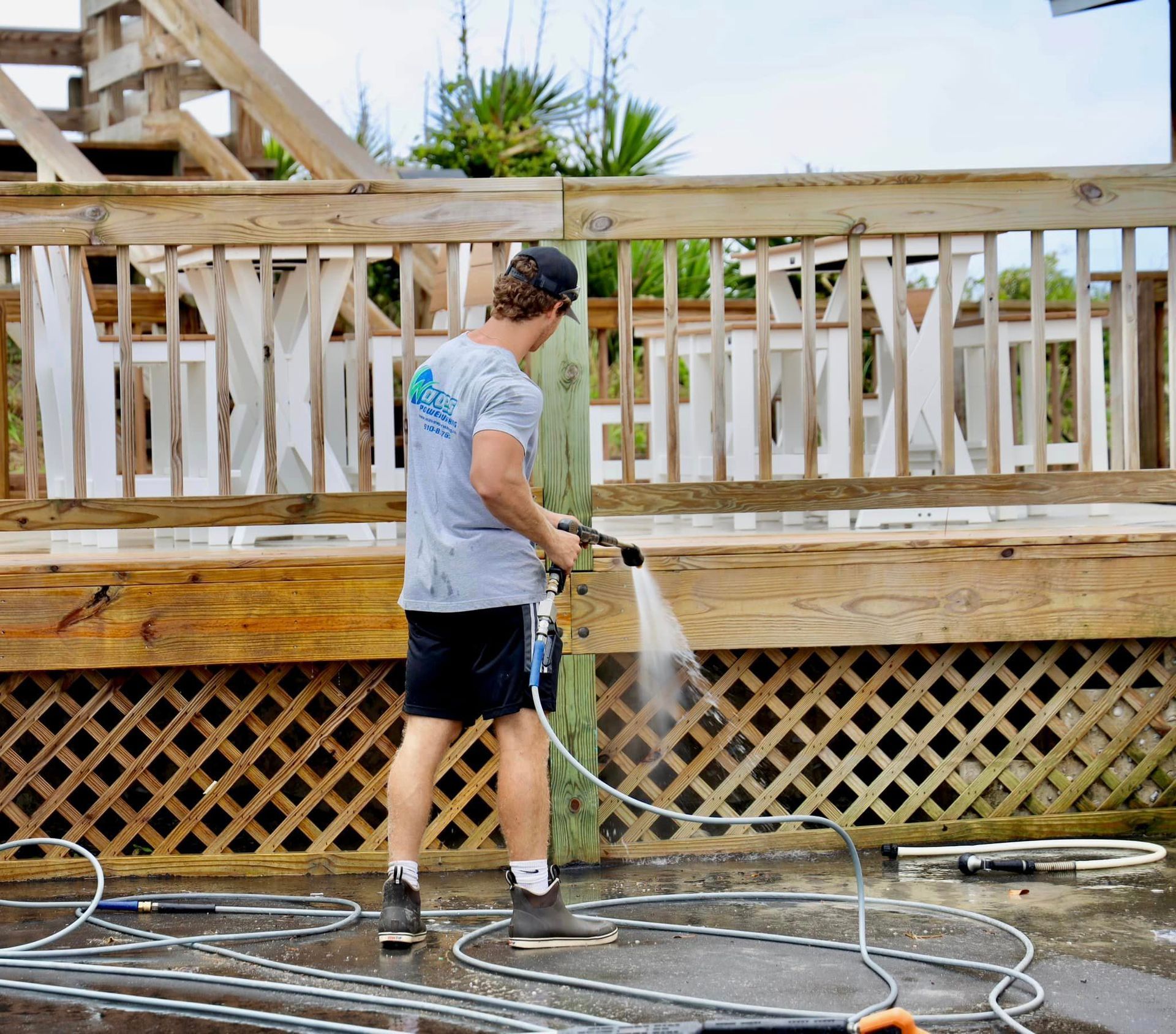 A man is using a high pressure washer to clean a deck.