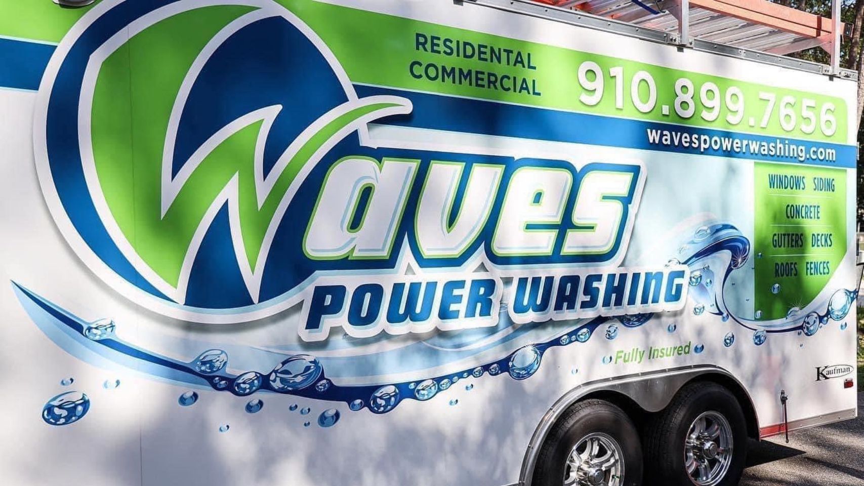 A waves power washing trailer is parked on the side of the road.