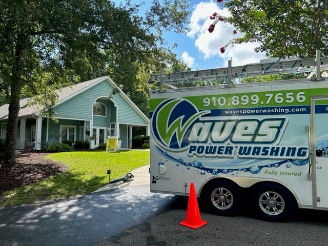 A waves power washing truck is parked in front of a house.
