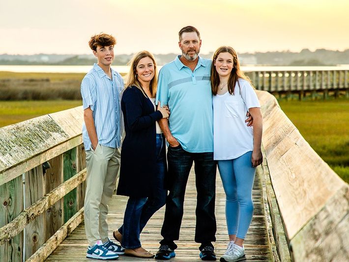 A family is posing for a picture on a wooden bridge.