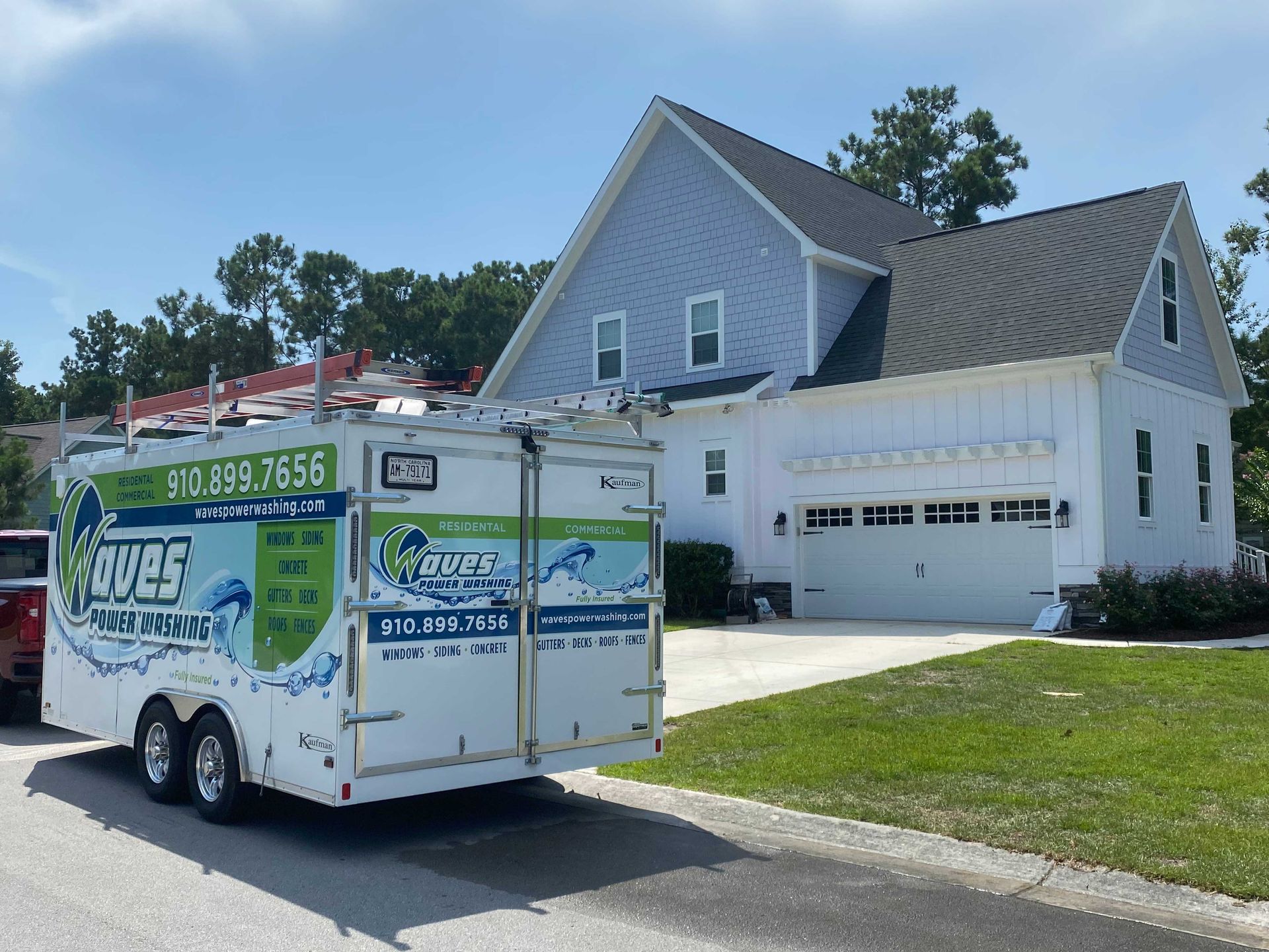 A white trailer is parked in front of a house.