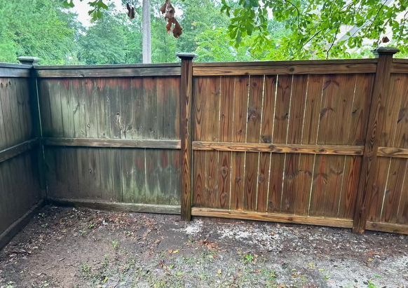 A wooden fence being cleaned by waves power washing.