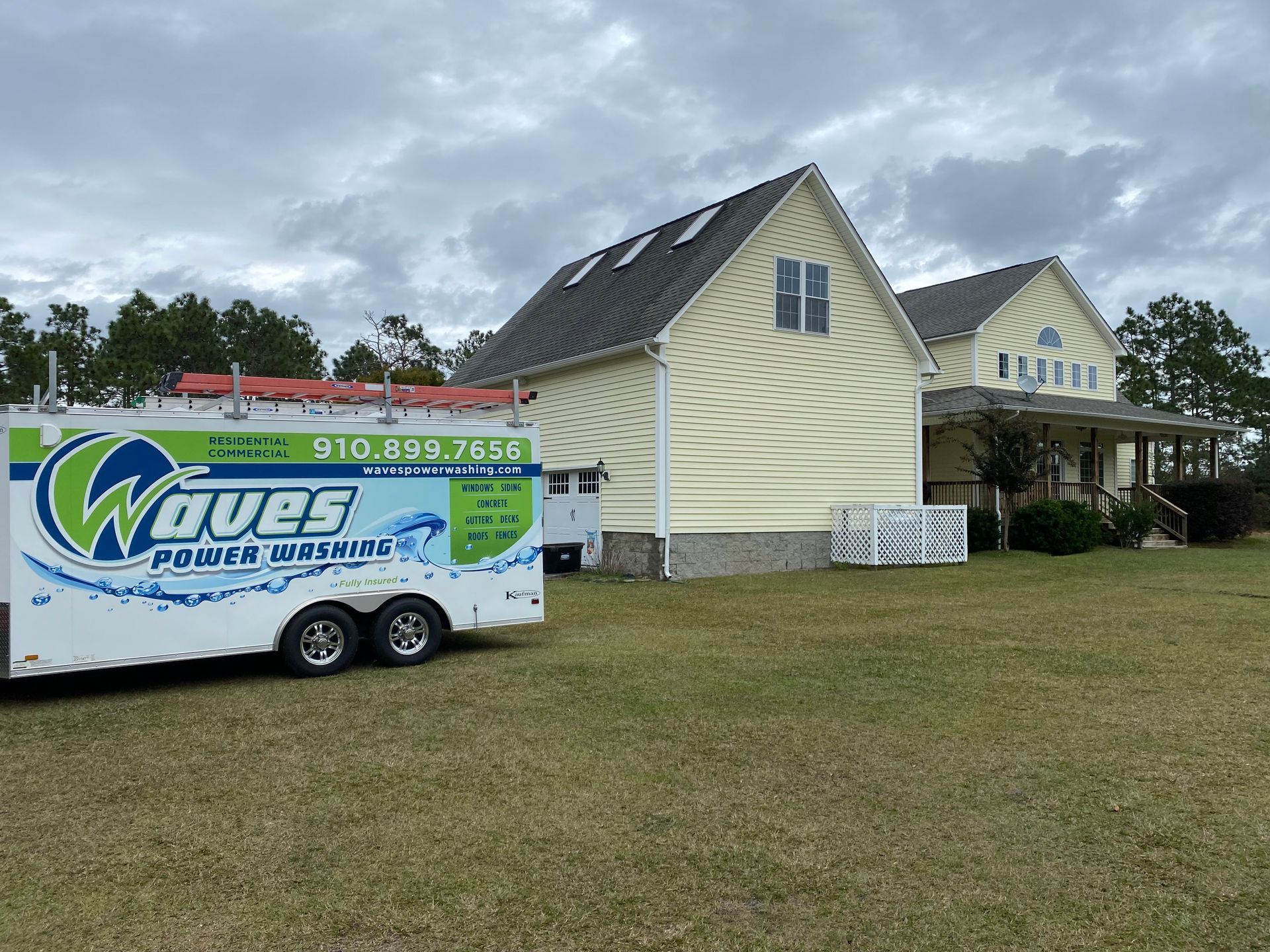 A trailer with the word waves on it is parked in front of a house.