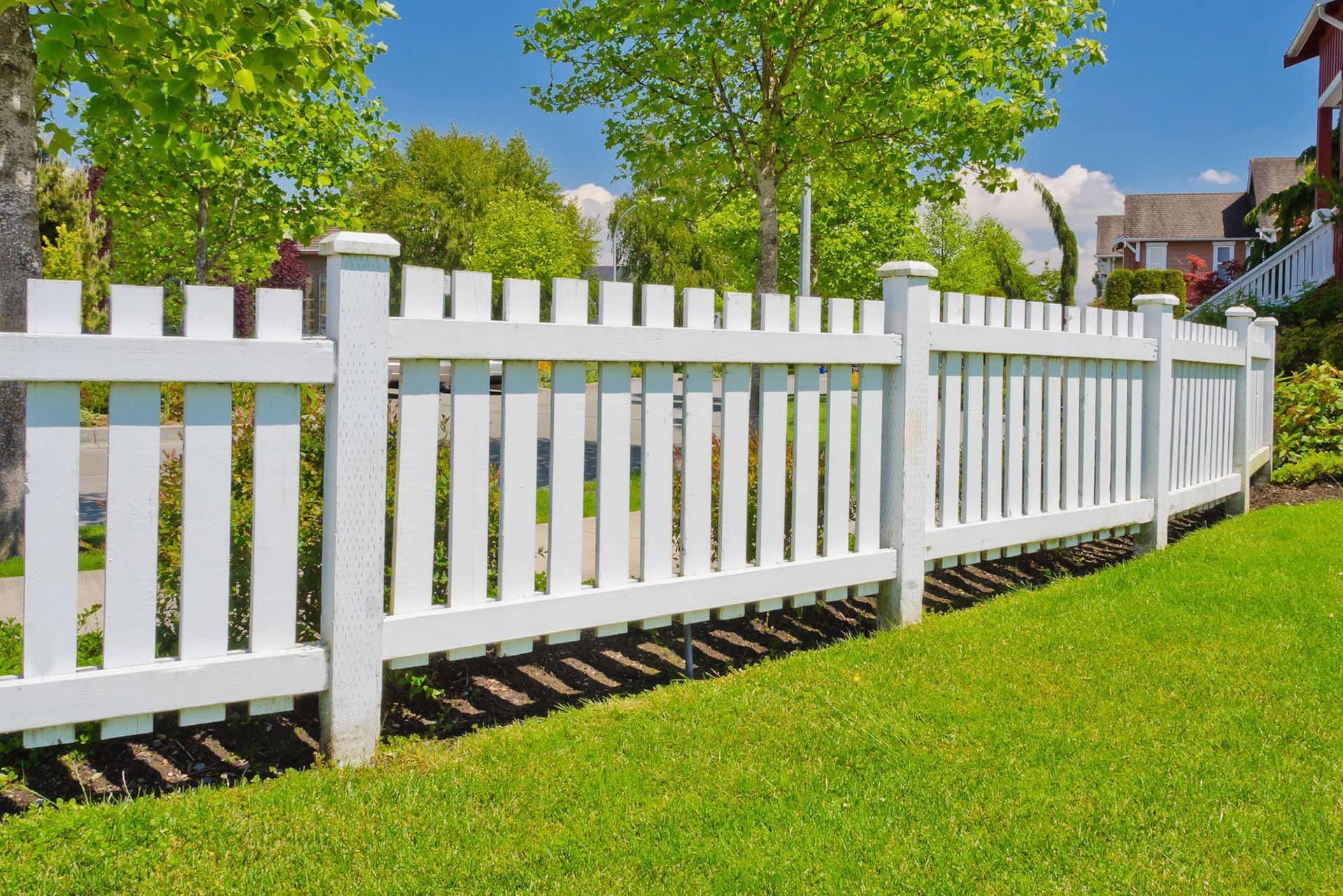 A white picket fence surrounds a lush green lawn.