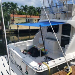 A white boat with a blue canopy is docked at a dock.