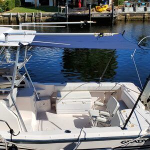 A white boat with a blue canopy is docked in the water.