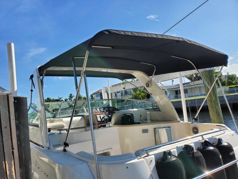 A boat with a black canopy is docked at a dock.