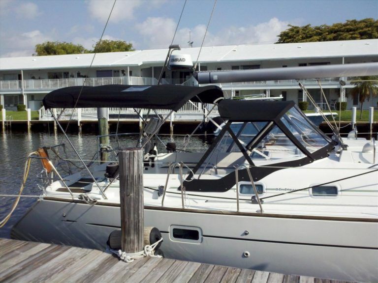 A sailboat with a black canopy is docked at a dock