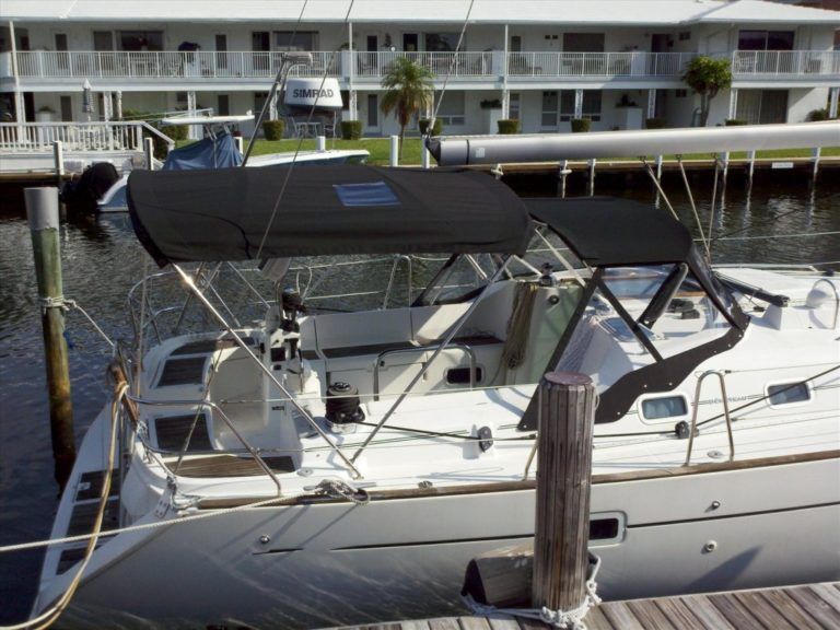 A white boat with a black canopy is docked at a dock