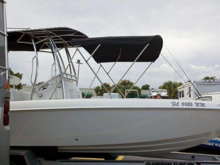 A white boat with a black canopy is on a trailer