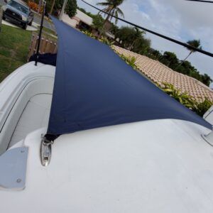 A blue sail is sitting on top of a white boat.