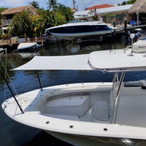 A white boat is docked in a marina next to a large boat.