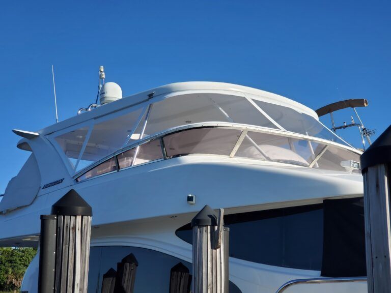 A white boat is docked at a dock with a blue sky in the background.